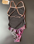 Flower of life One-Piece Swimsuit in black lying on a black surface shown from the back for more details to the open back and adjustable straps.