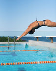 Female model wearing the Hailey One-Piece Swimsuit mid-air while jumping into the pool, showcasing the swimsuit's secure and flexible design.