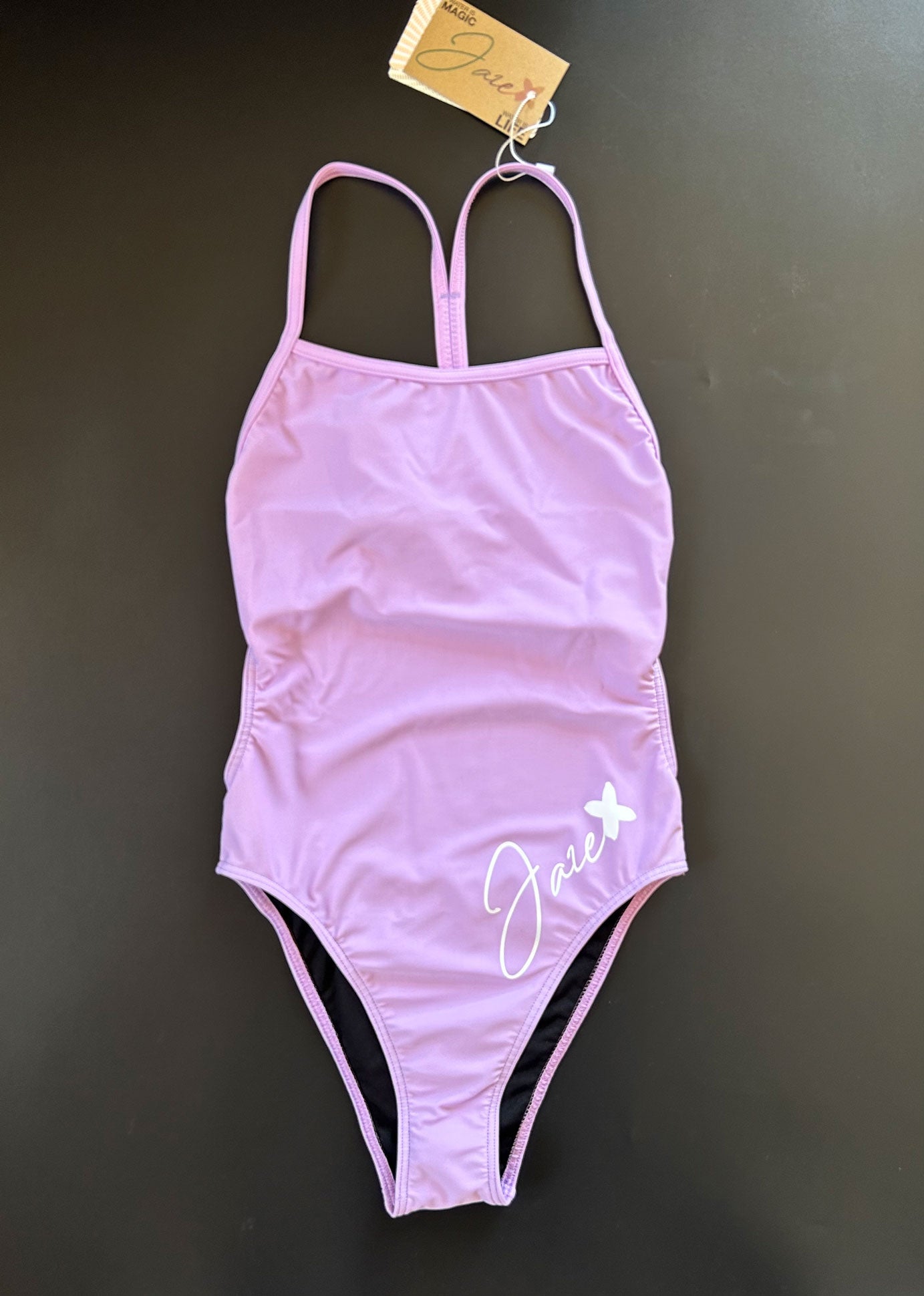 Our Lavender One-Piece-Swimsuit lying on a black surface shown from the front.