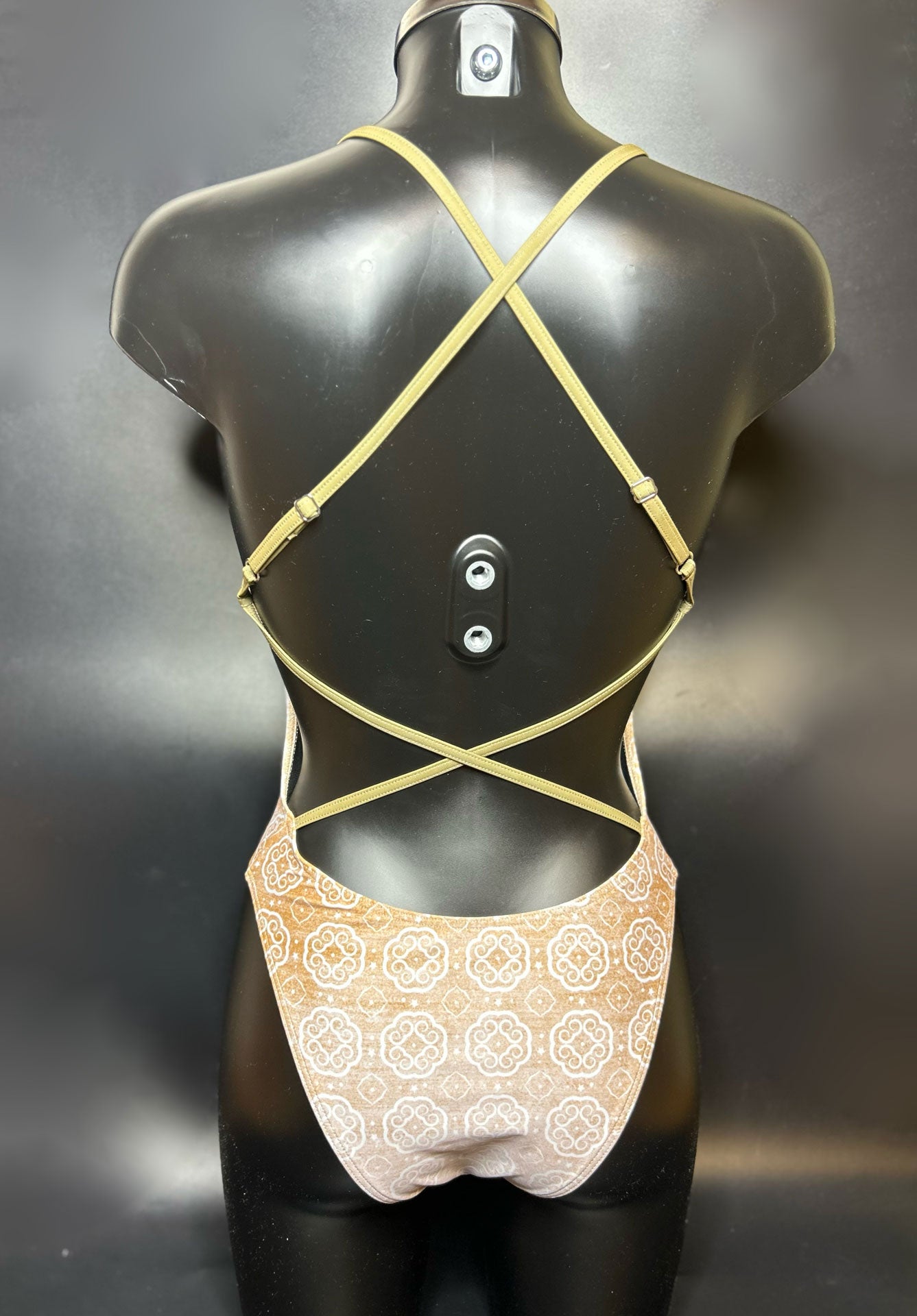 Lana one piece swimsuit on a mannequin shown from the back with a black background showing the open back and adjustable straps.