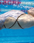 Under water photo from our Lana one piece swimsuit shown from the side with our model backstroking in the pool.