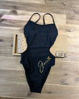 The MAYA - One-Piece Swimsuit lying on a wooden floor and shown from the front.