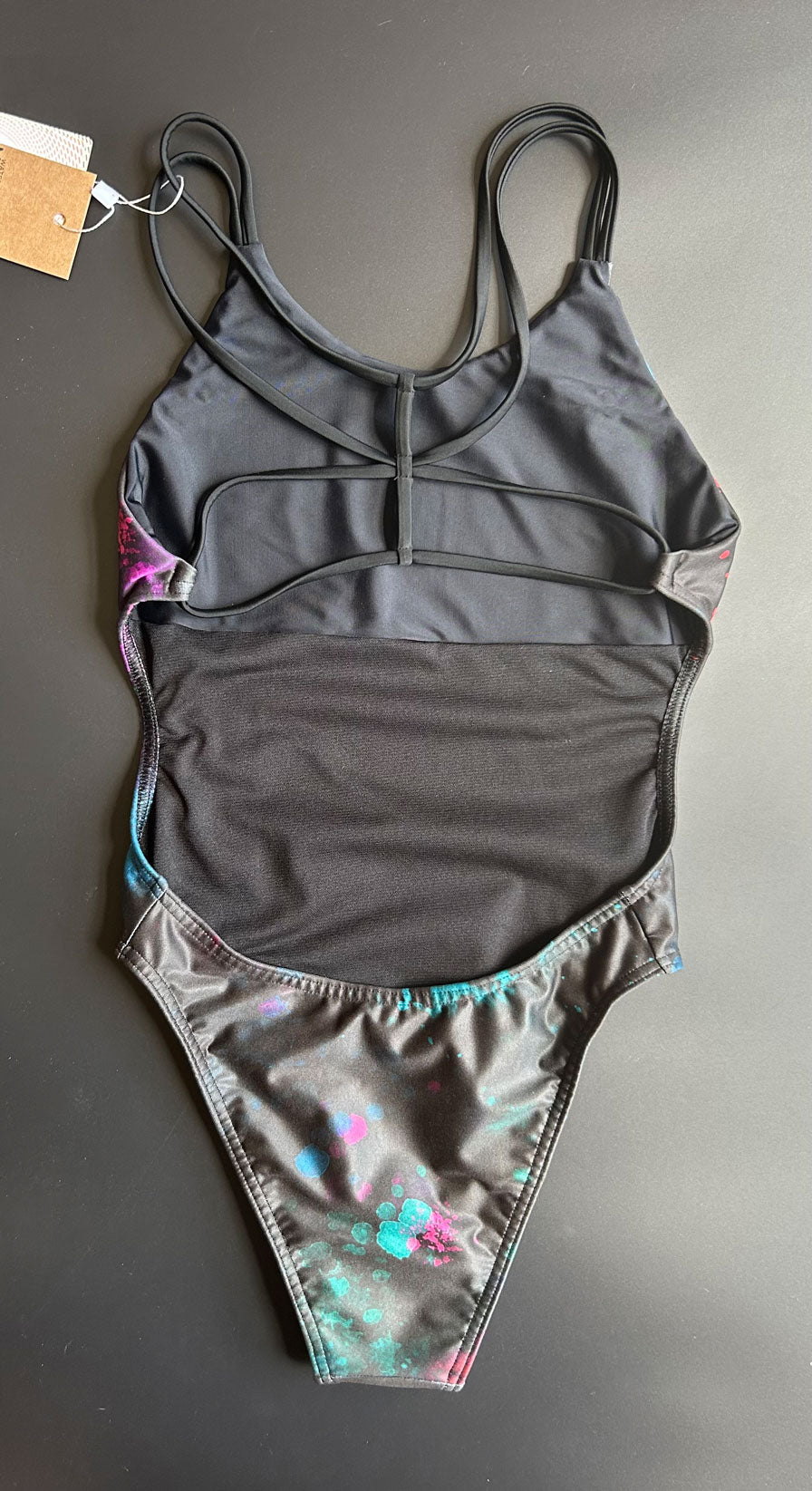 Back view of the Universe Swim Onesie on a black background, featuring the open-back cut and elegant fit.