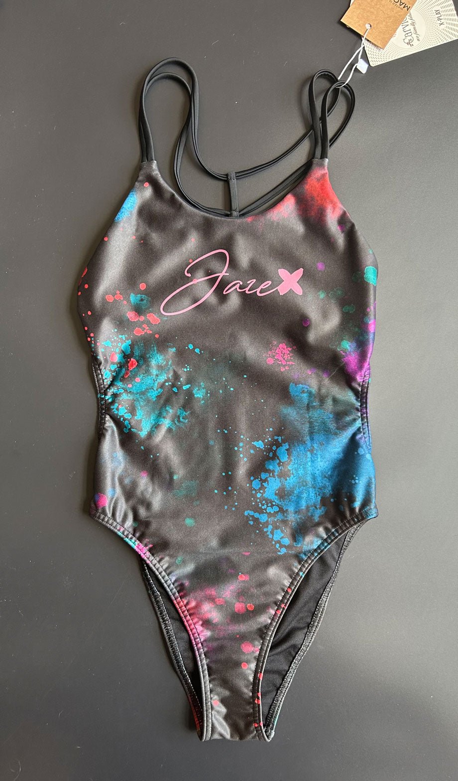Universe Swim Onesie displayed on a black background, showing the galaxy print and streamlined front design.