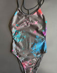 Universe Swim Onesie displayed on a black background, showing the galaxy print and streamlined front design.