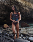 Female model wearing the Universe Swim Onesie at the sea, showcasing the sleek design and galaxy-inspired pattern from the front.
