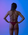 Female model standing in front of a colorful background shown from the front, hands on her hips, showing the open back and adjustable straps for perfect fit.