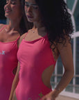 Jaze Maya one piece swimsuit, sporty and premium quality in color coral, shown on our model walking towards the camera, cut outs on the side