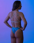 Back view of a female model wearing a Zebra Blue one-piece swimsuit, featuring an open-back design and secure fit.