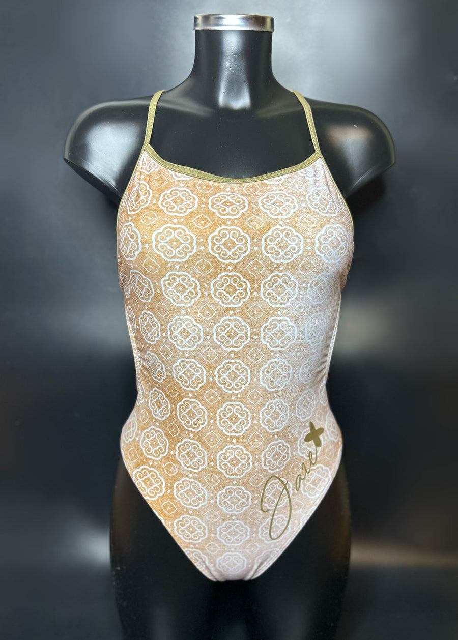 Lana one piece swimsuit on a mannequin in the color gold and white shown from the front with a black background.