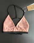 The peach Sunrise – Bikini top shown from the front comes with thin black straps.