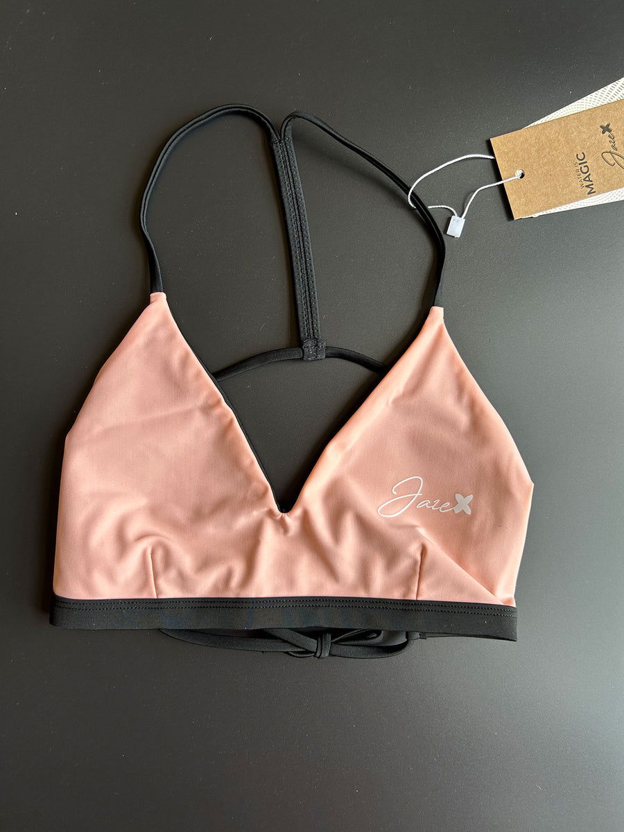 The peach Sunrise – Bikini top shown from the front comes with thin black straps.