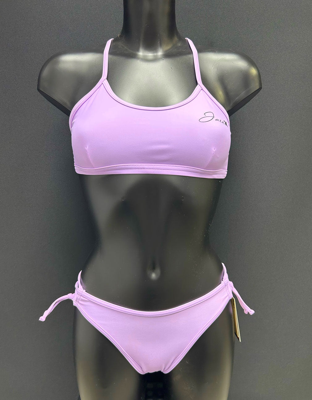 Jaze Ariel bikini bottom in lavender on a mannequin, front view showing adjustable side straps and sleek performance design.