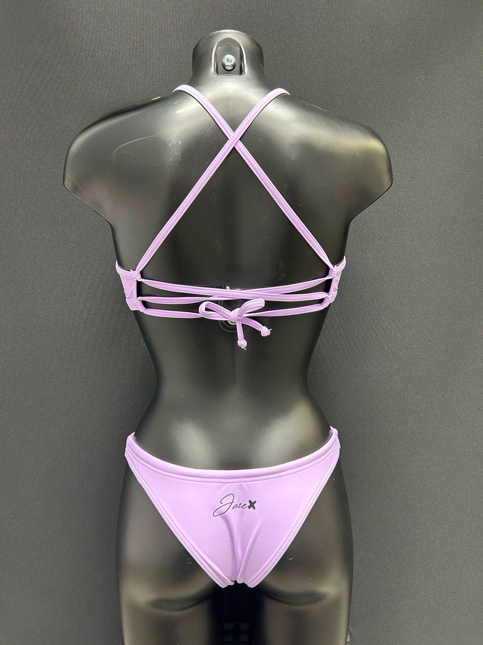 Back view of cheeky bikini bottom in color lavender by Jaze on mannequin, highlighting minimal coverage and premium sustainable fabric built for active training.