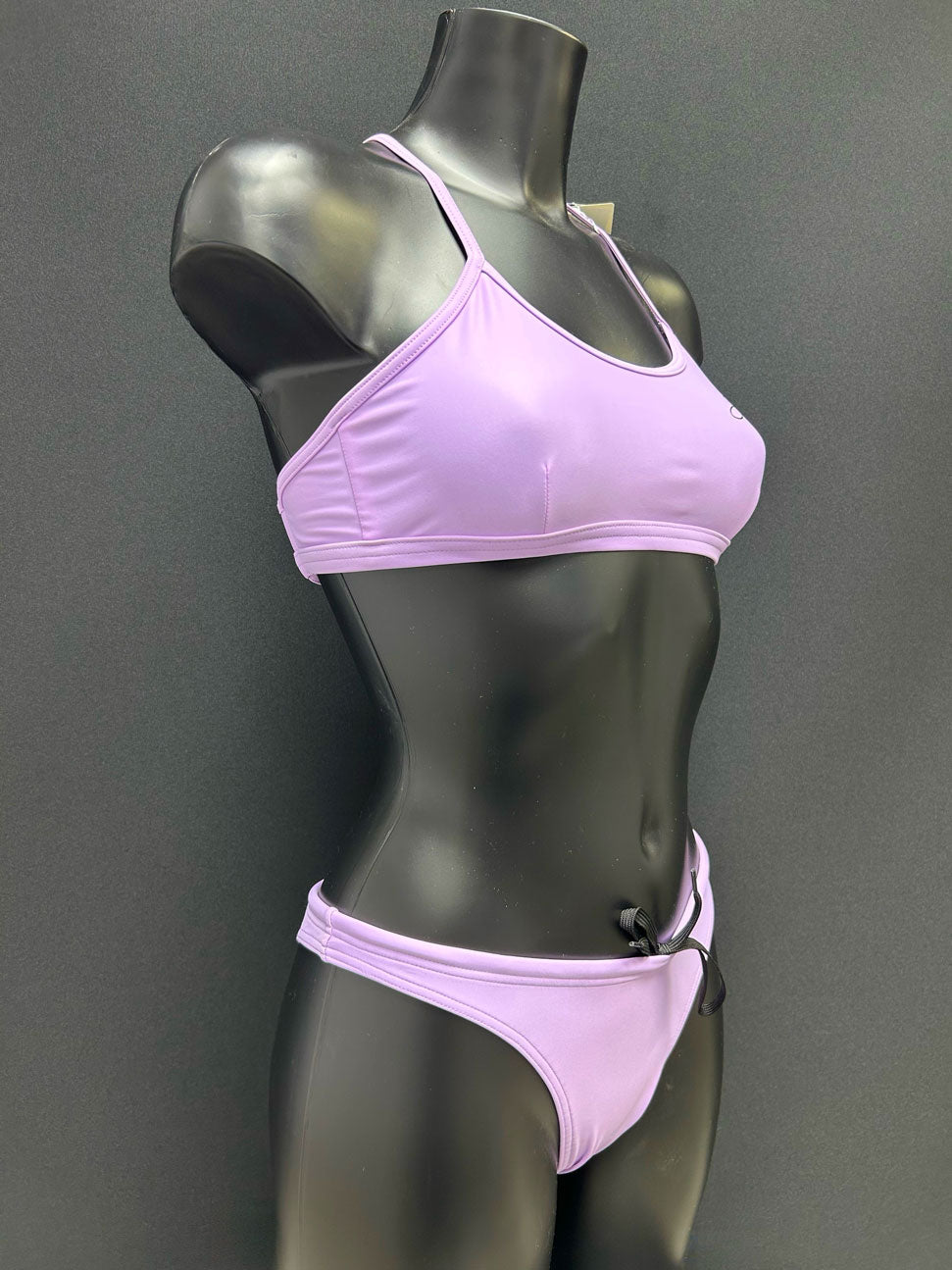 Side view of performance bikini bottom in color lavender by Jaze on mannequin, showing secure fit and soft eco-friendly Italian fabric for swimmers.